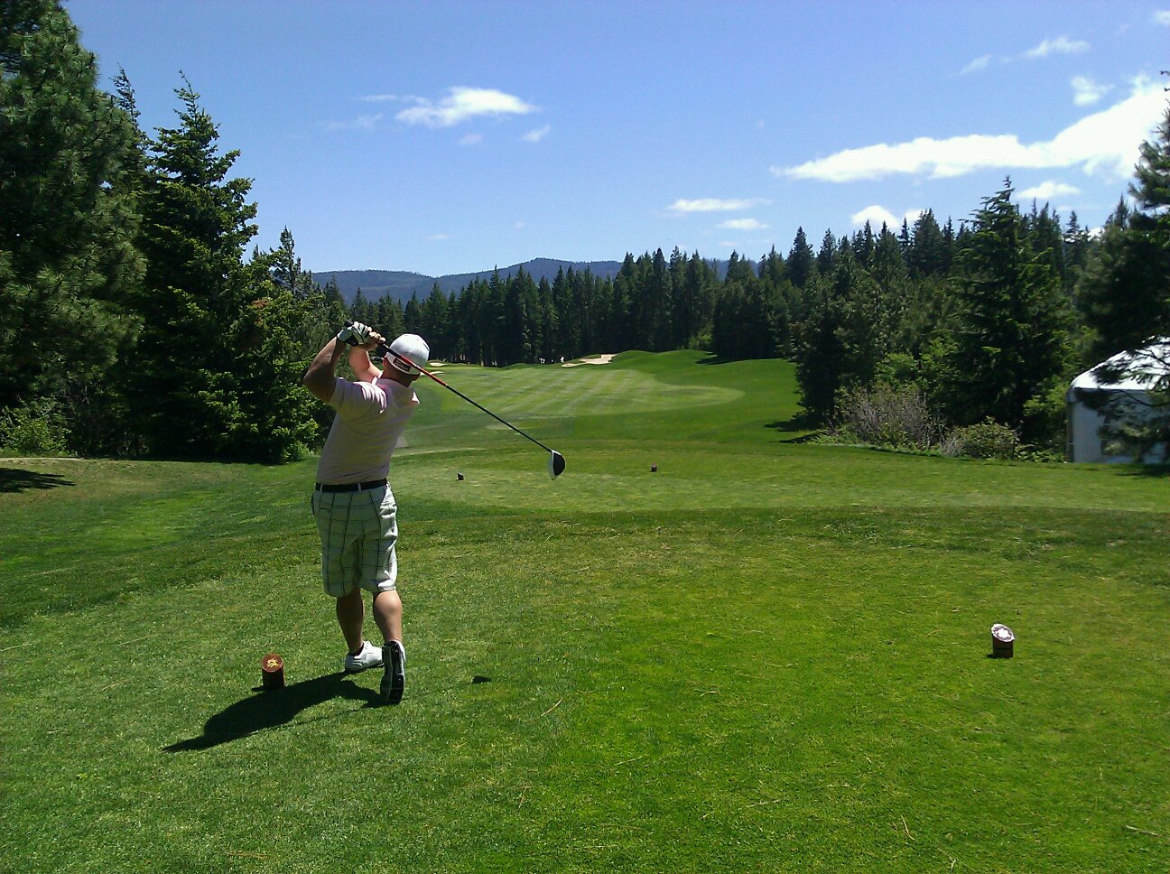 Golfer mid-swing at the top of the backswing.